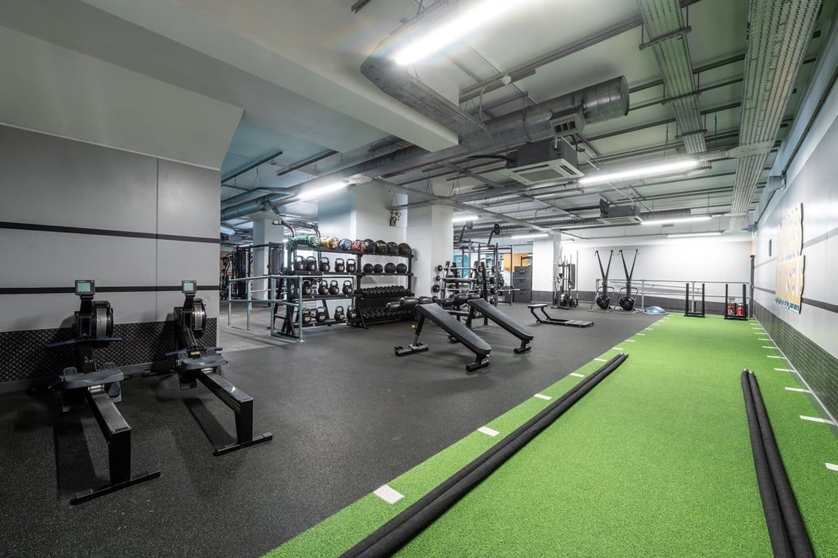 PureGym Stevenage: Weights racks, benches, turf area, resistance bands, rubberized floors in a gym studio.