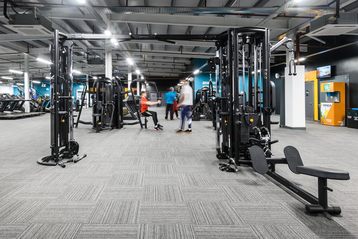 PureGym Cambridge Grafton Centre: Multi-station weight machines, benches, rubberised flooring in a brightly lit gym interior.