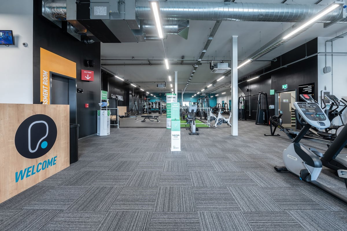PureGym Birmingham Longbridge: Rows of treadmills, stationary bikes, and weight machines in a modern gym setting.