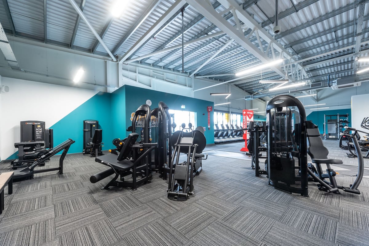 PureGym Barnsley: Resistance machines, weight racks, benches, and patterned rubberized flooring in a brightly lit gym space.