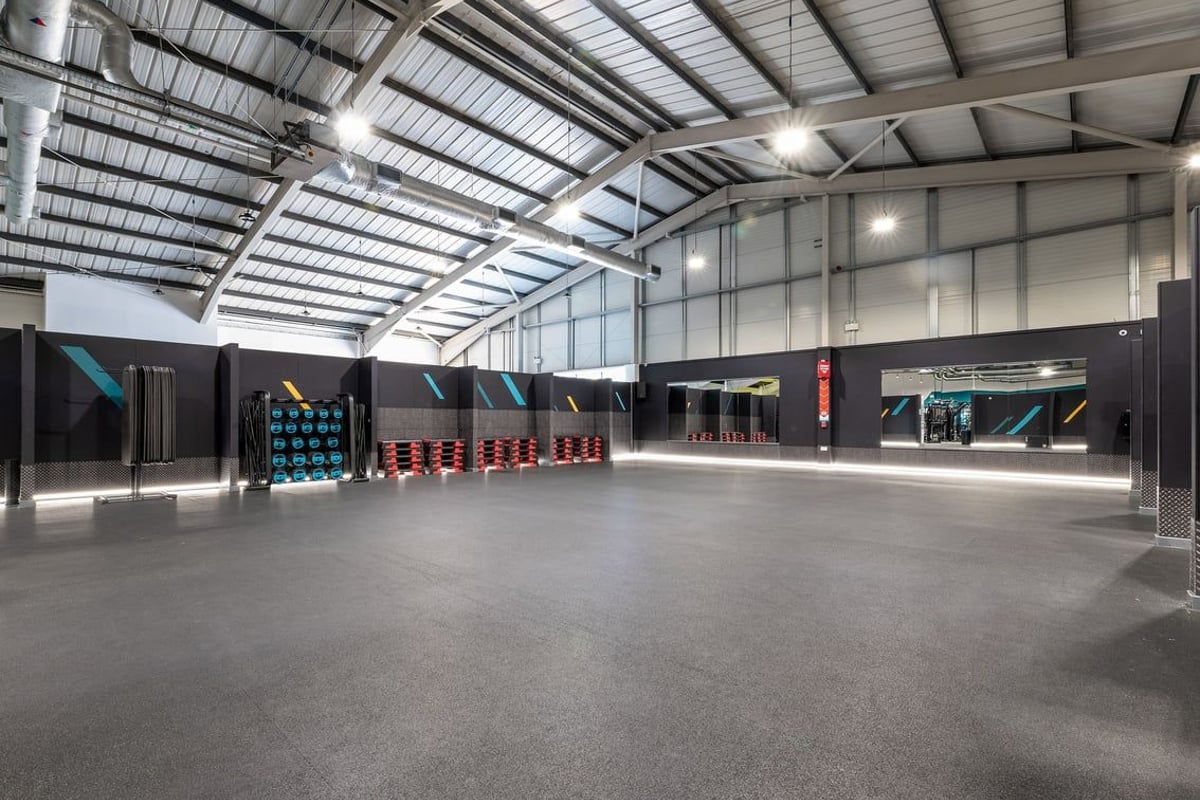 PureGym Leeds Bramley: Rows of colourful strength training rigs, rubberised floor, vaulted ceiling.