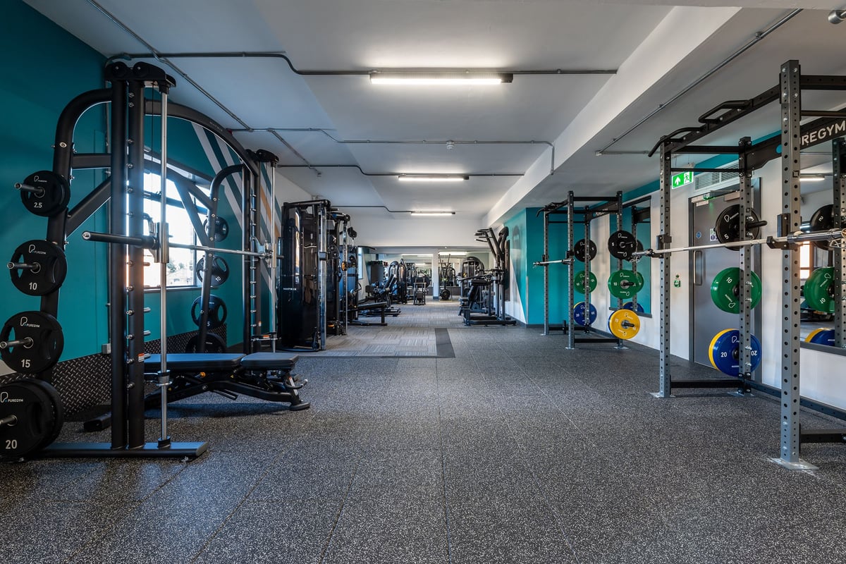 PureGym Southampton Bitterne: Squat racks, weight plates, weight benches, rubberized flooring in a teal and black gym studio.