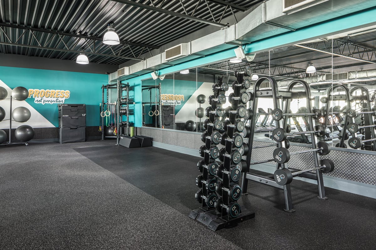 PureGym Dudley Tipton: Racks of dumbbells, kettlebells, weightlifting platforms, mirrored walls, teal branding.