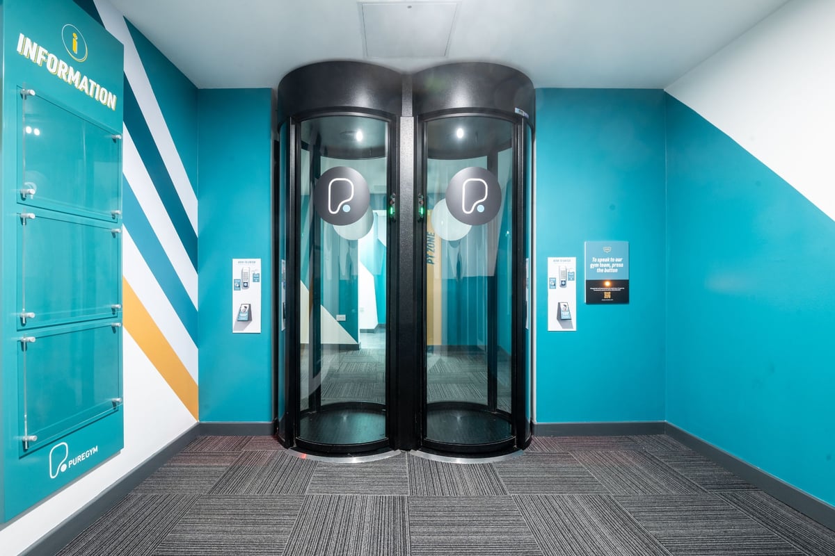PureGym Edinburgh Exchange Crescent: Two revolving security entrance gates in an information lobby.