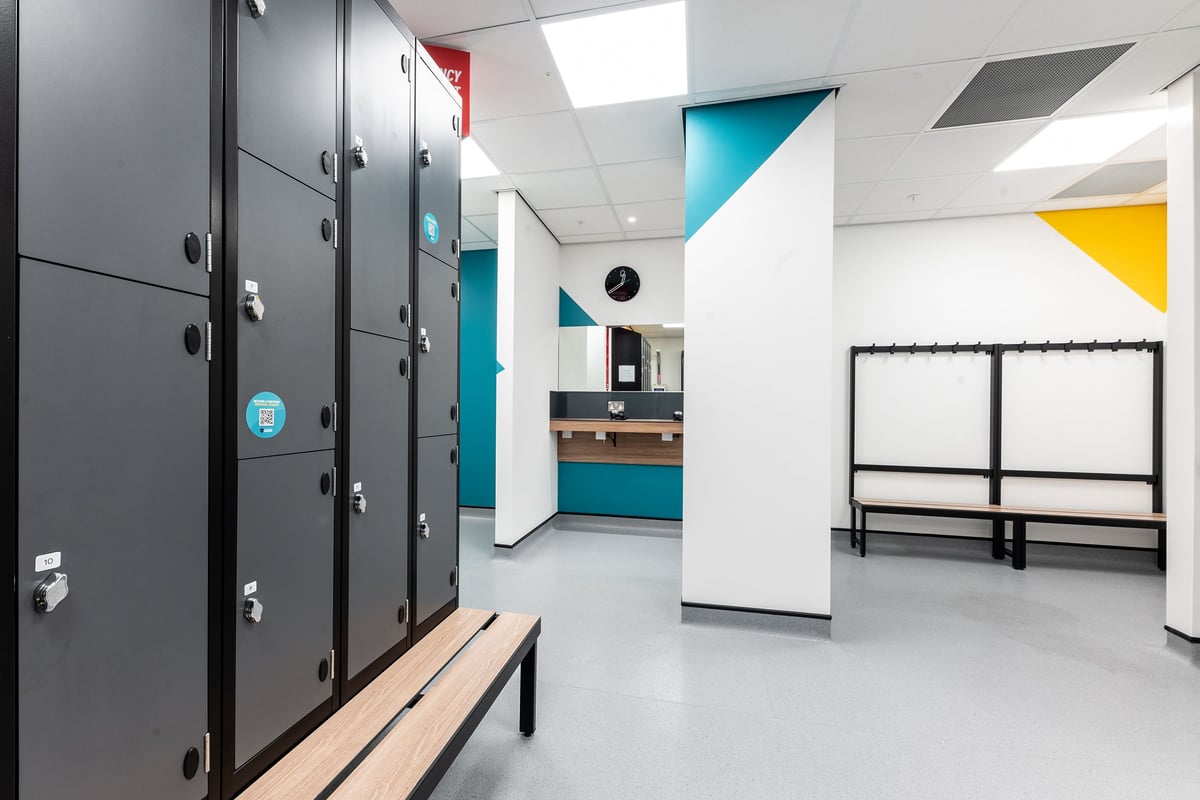 PureGym Hatfield: Lockers, benches, and geometric wall art in a modern changing room or lobby area.
