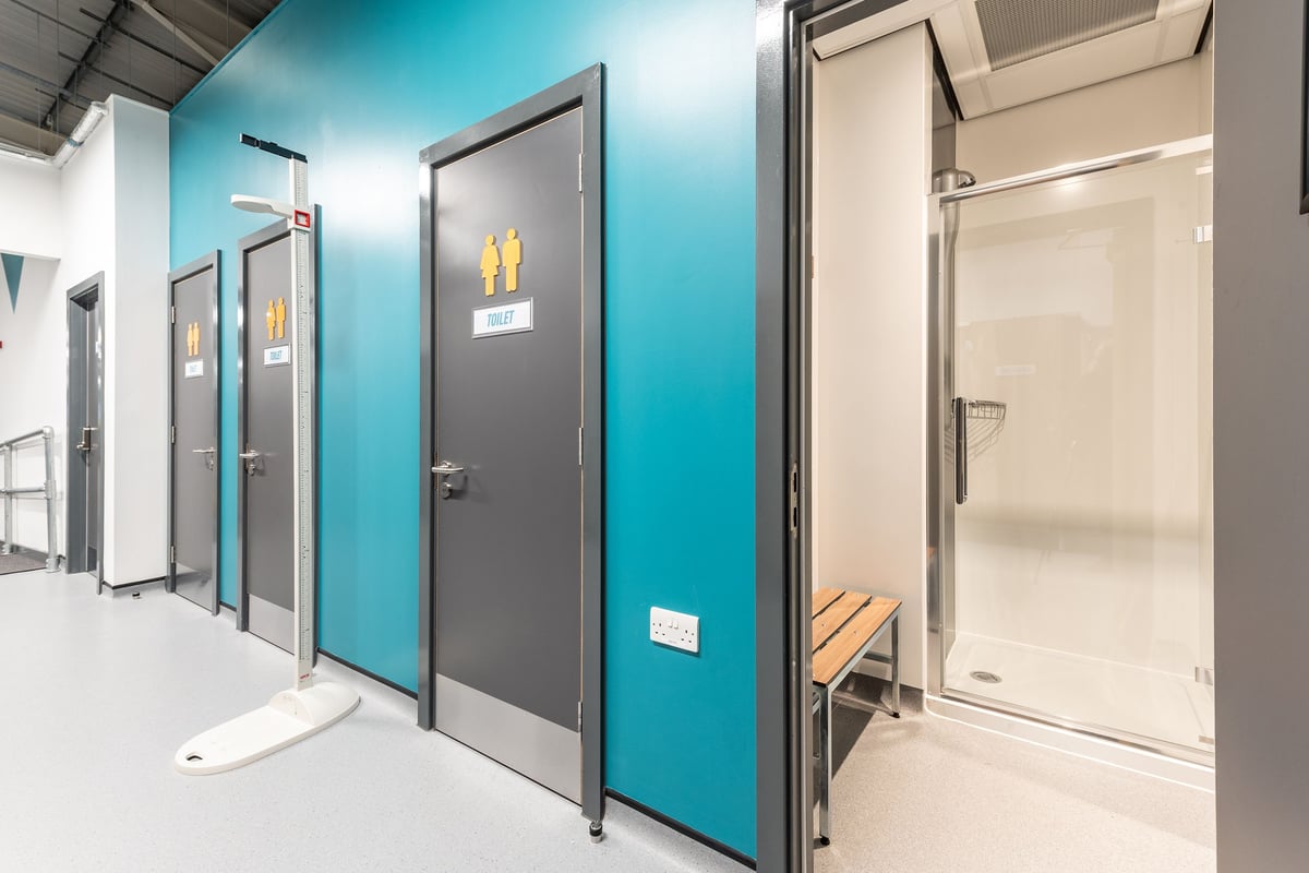 PureGym Newhaven: Changing rooms with metal doors and teal accent walls.
