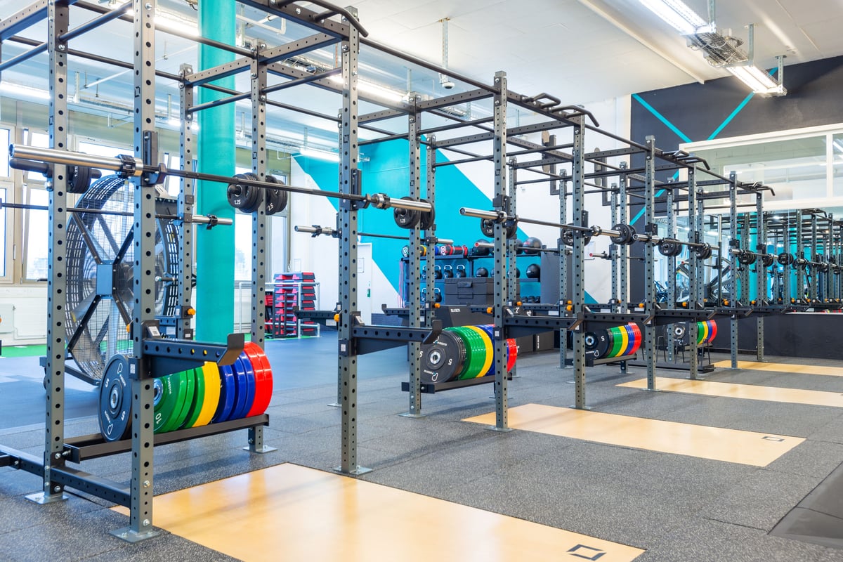 Gym Jona Squat-Rack-Bereich mit mehreren Racks und bunten Gewichtsscheiben