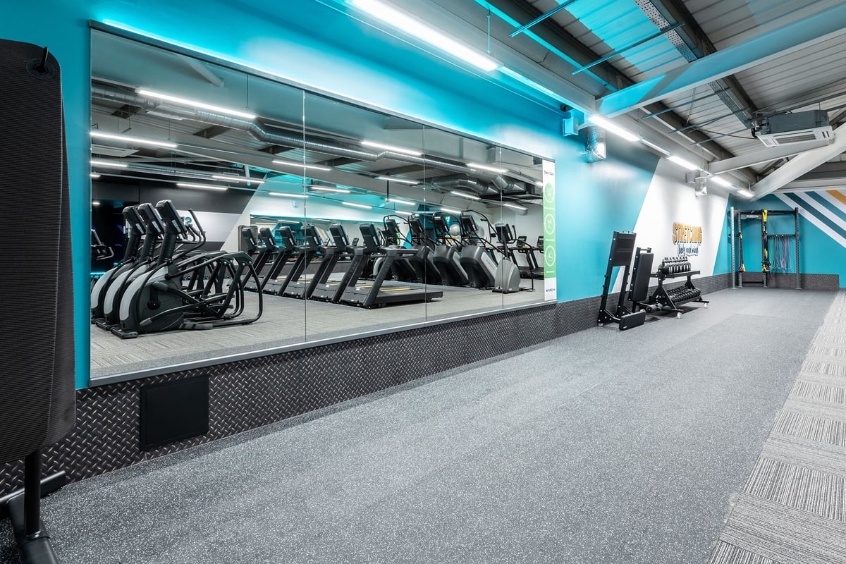 PureGym Milton Keynes Kingston Centre: Rows of treadmills and exercise bikes in a brightly lit teal-coloured gym studio.