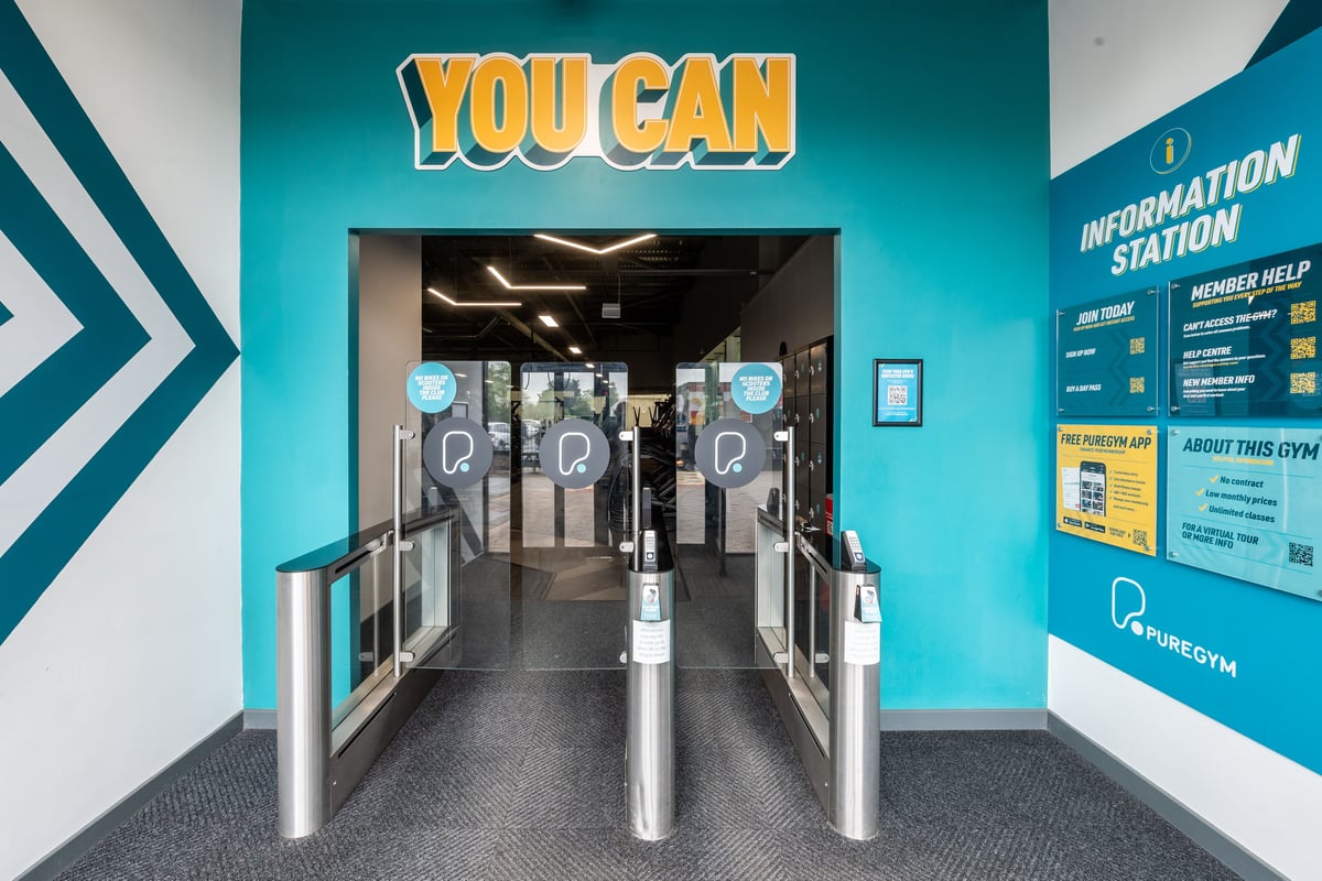 PureGym Peterborough Serpentine Green Shopping Centre: Turnstiles leading into gym area with information station.