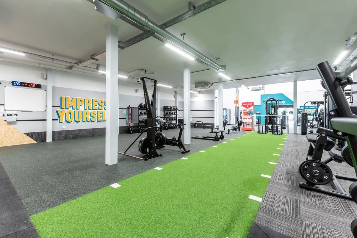 PureGym Northallerton: Functional training area with green turf, free weights, resistance machines and wall graphics.