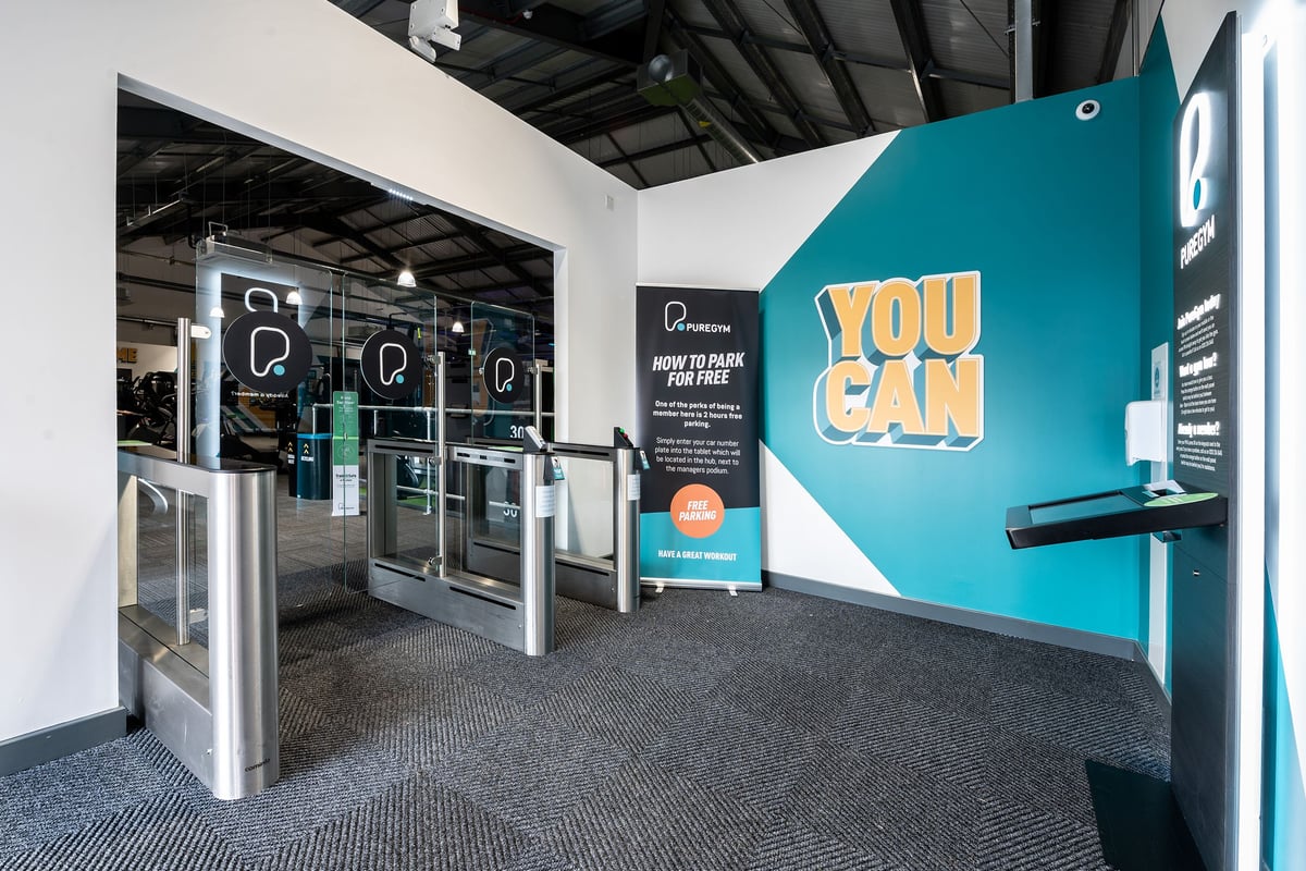 PureGym Stowmarket: Gym entrance area with turnstiles, motivational signage, and teal branding.