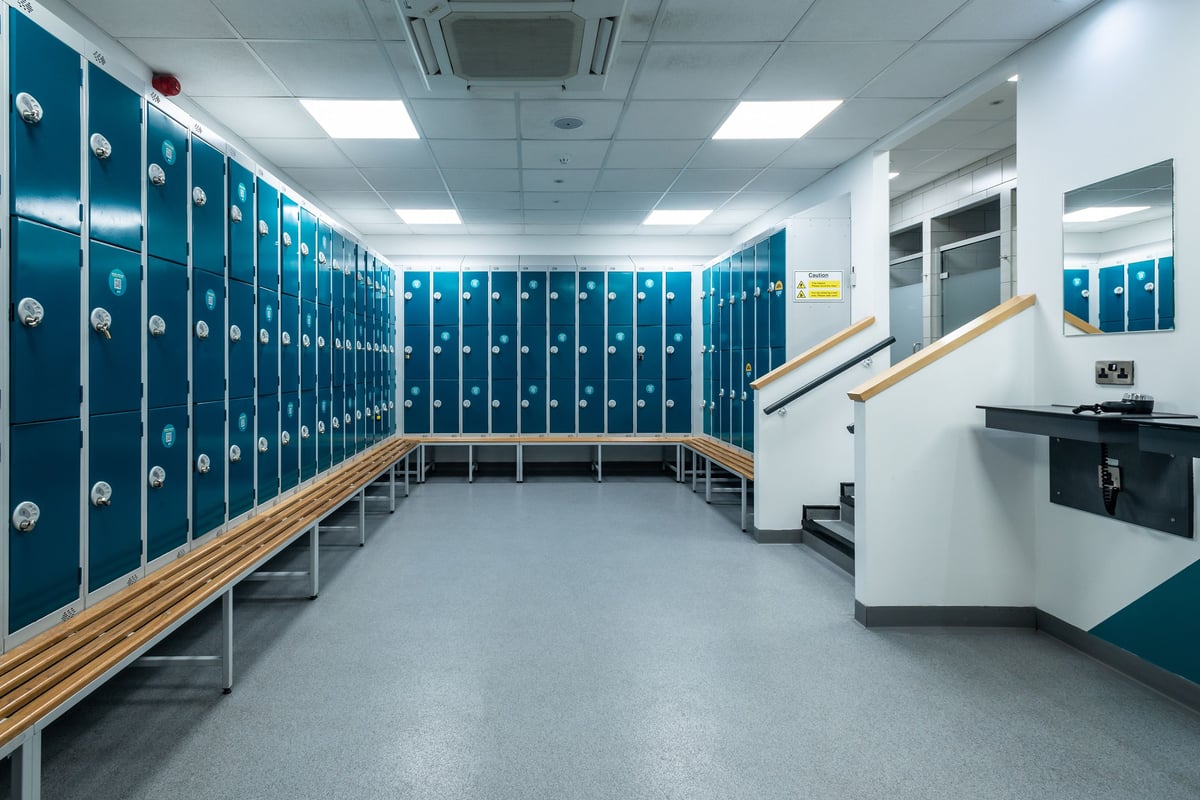 PureGym Wrexham: Rows of navy lockers, wooden benches, and tile flooring characteristic of changing rooms.