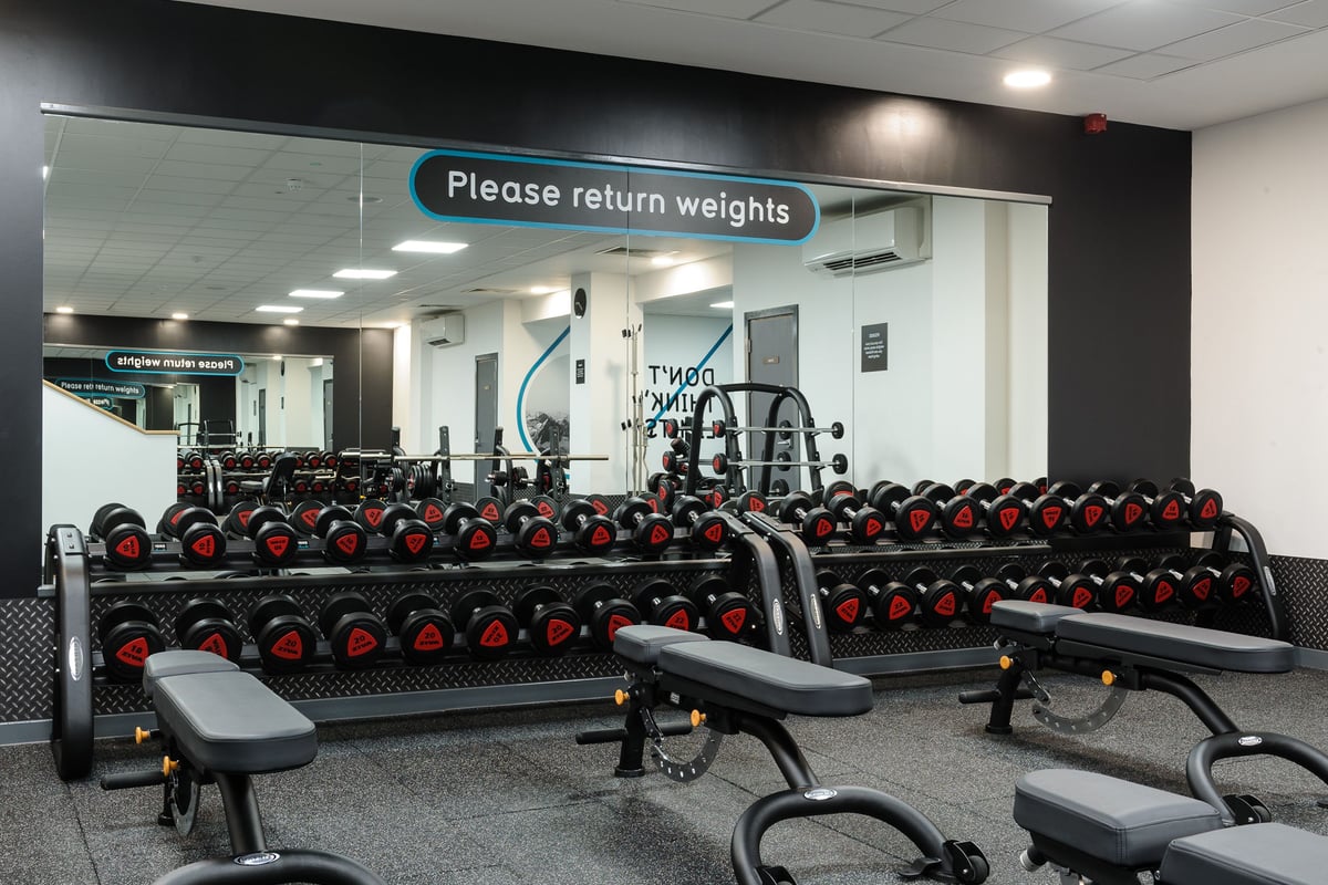 PureGym Billericay: Rows of dumbbell racks with weights, benches, and signs asking to return weights.