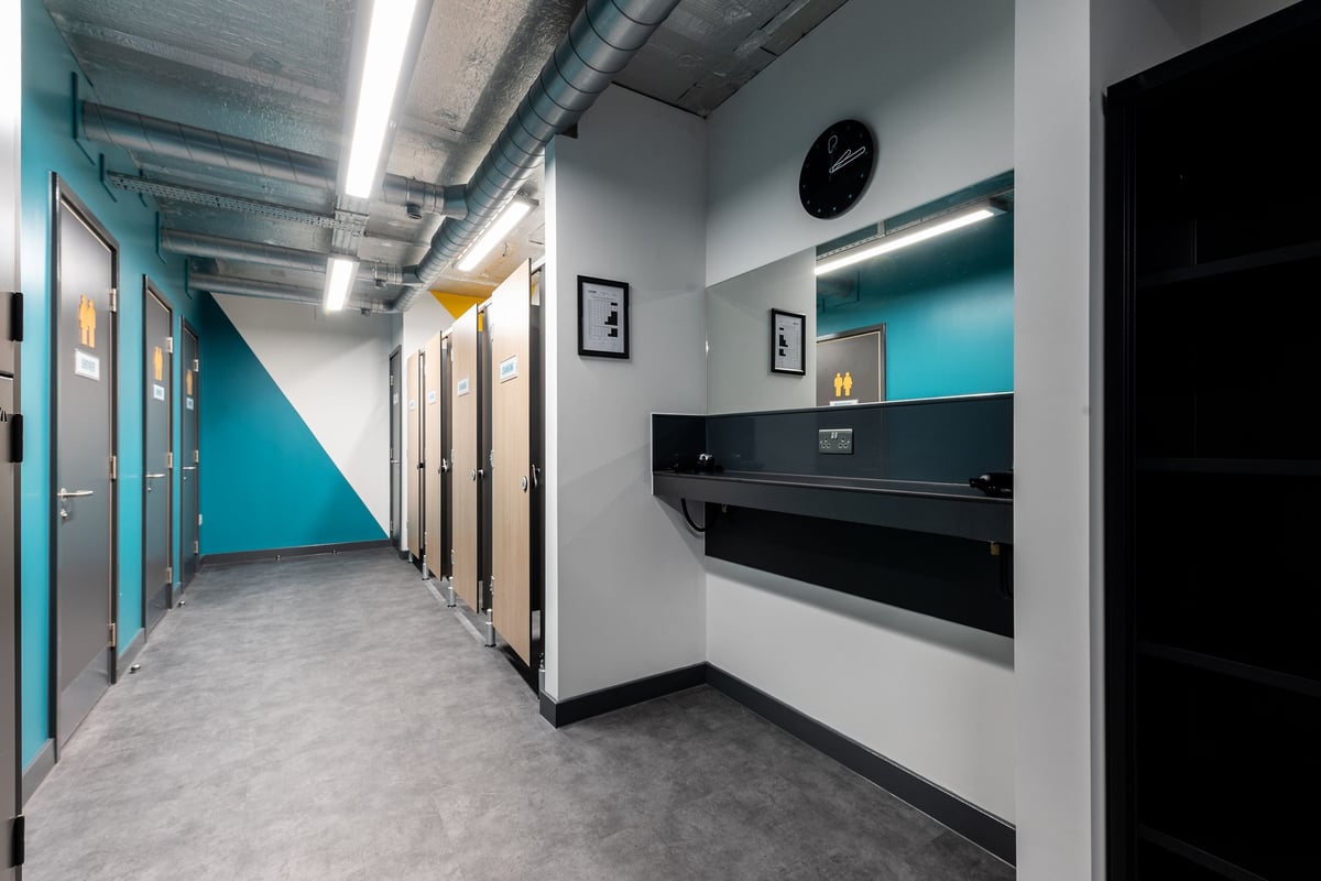 PureGym London Seven Sisters: Gym locker room with privacy cubicles, hair dryers, and mirrors.