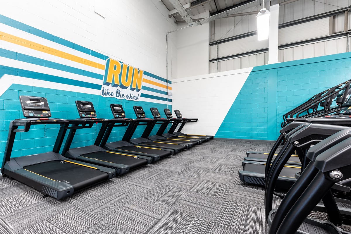 PureGym Dagenham: Rows of treadmills alongside colourful striped wall branding reading "RUN like a boss".