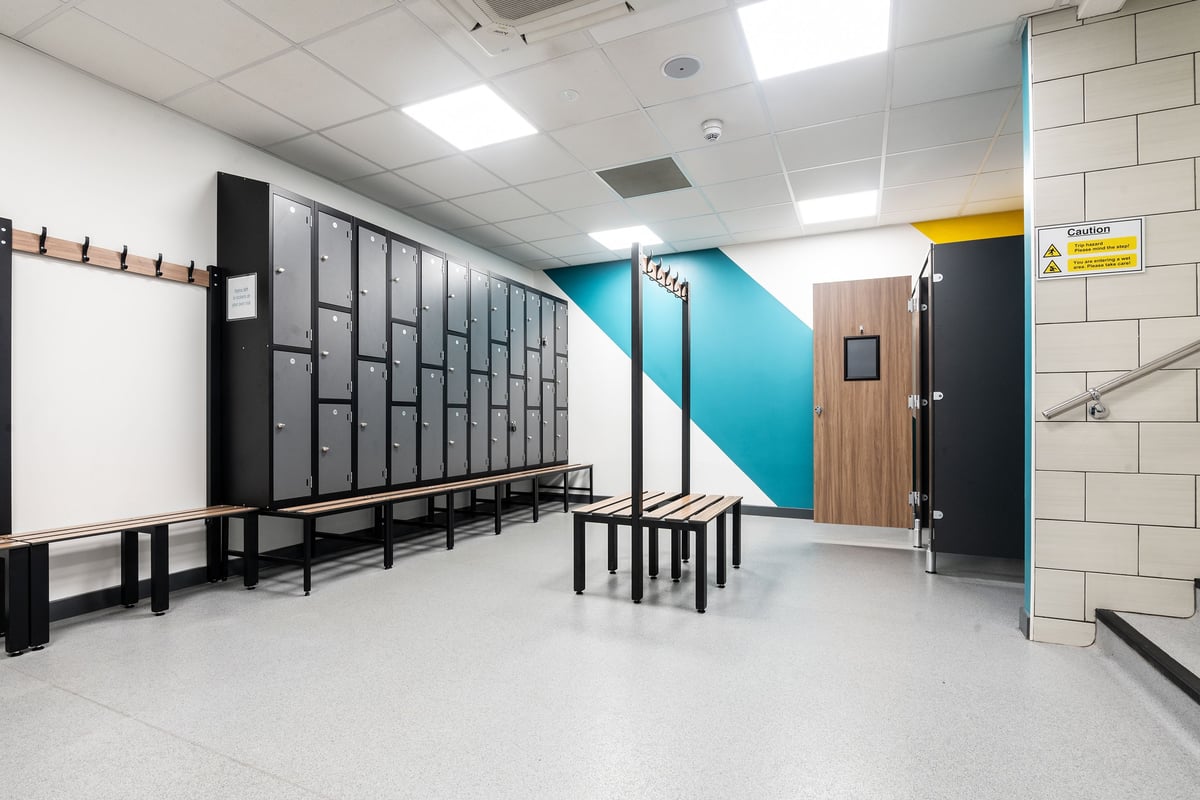 PureGym Aberdeen Kittybrewster: Rows of lockers, benches and blue accent wall in a changing room interior.