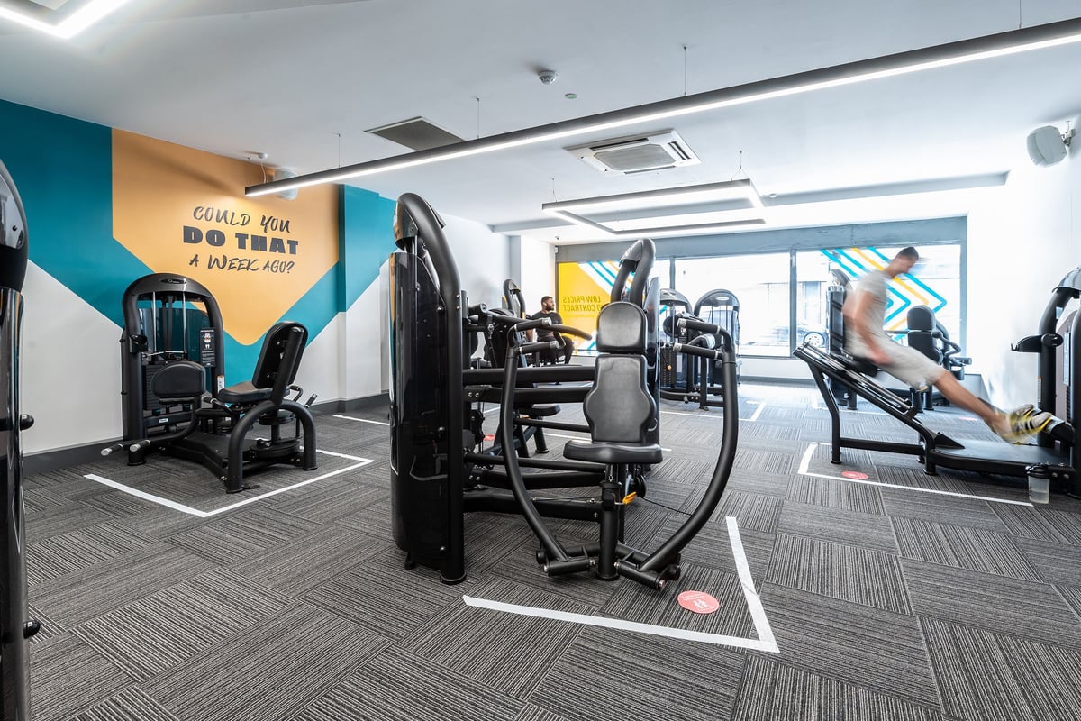 PureGym London Sydenham: Gym studio with resistance machines, benches, rubberized flooring, and motivational wall graphics.