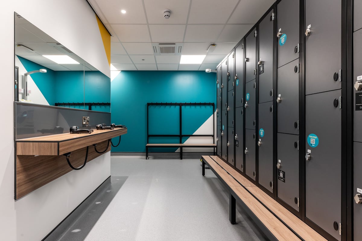 PureGym Shrewsbury Meole Brace: Rows of lockers, benches, turquoise walls, and rubberized flooring.