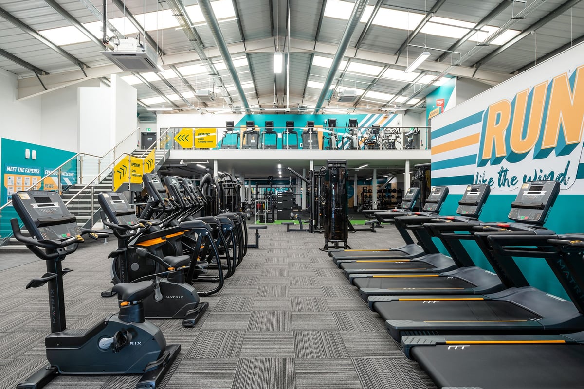 PureGym Cannock Orbital Retail Park: Rows of treadmills, ellipticals, and weight machines in a brightly lit fitness studio.