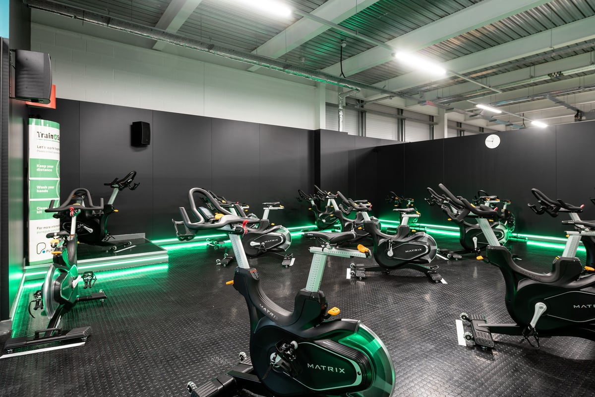 PureGym Andover: Rows of stationary bikes with neon green lighting in a dimly lit studio.