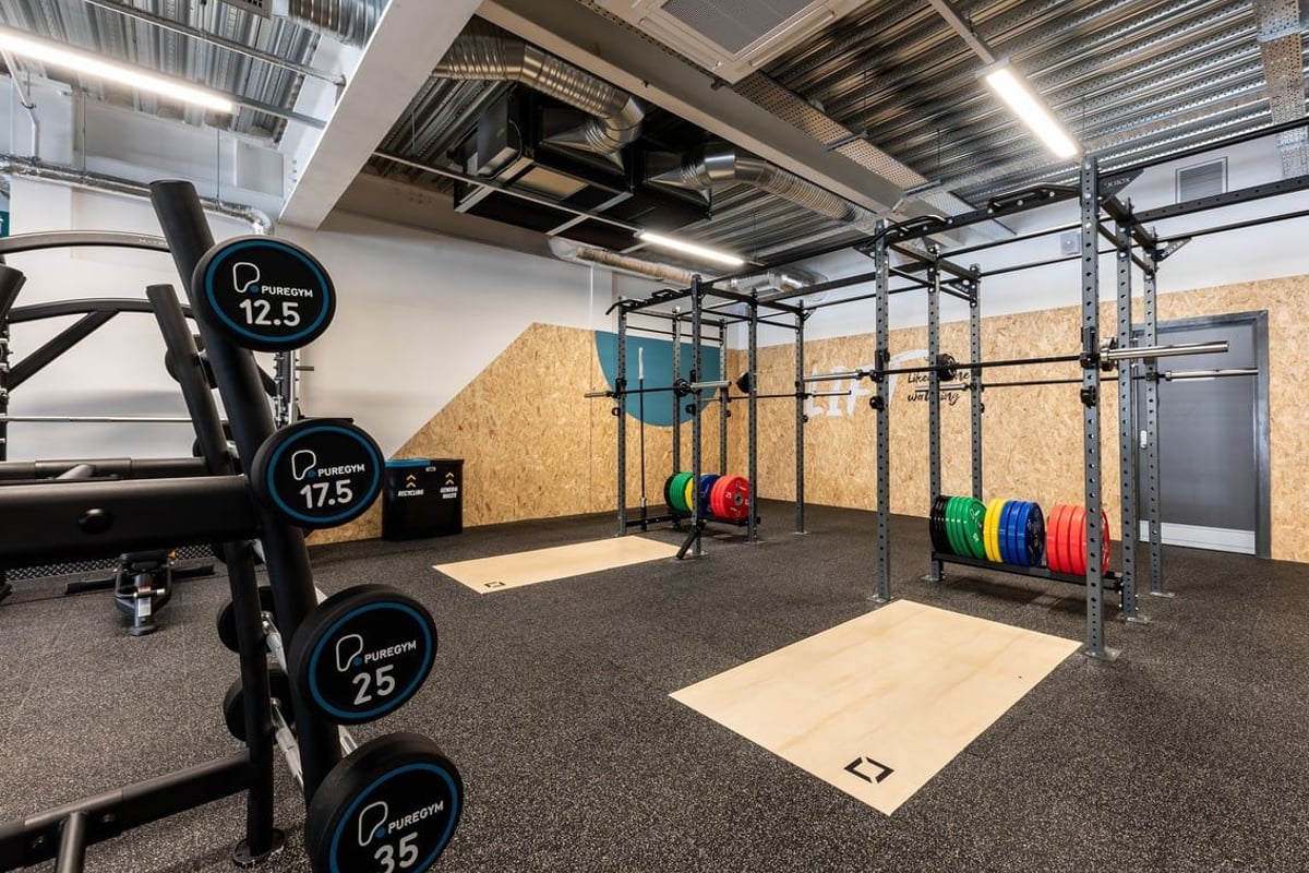 PureGym Yate: Rig with weight plates, barbells, racks, rubberized flooring for weightlifting and functional training.