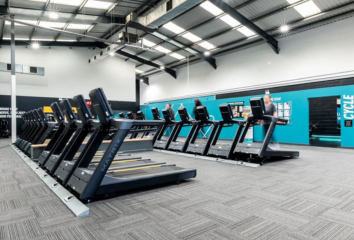 PureGym Leeds Hunslet: Rows of treadmills and exercise bikes lined up in a spacious gym interior.