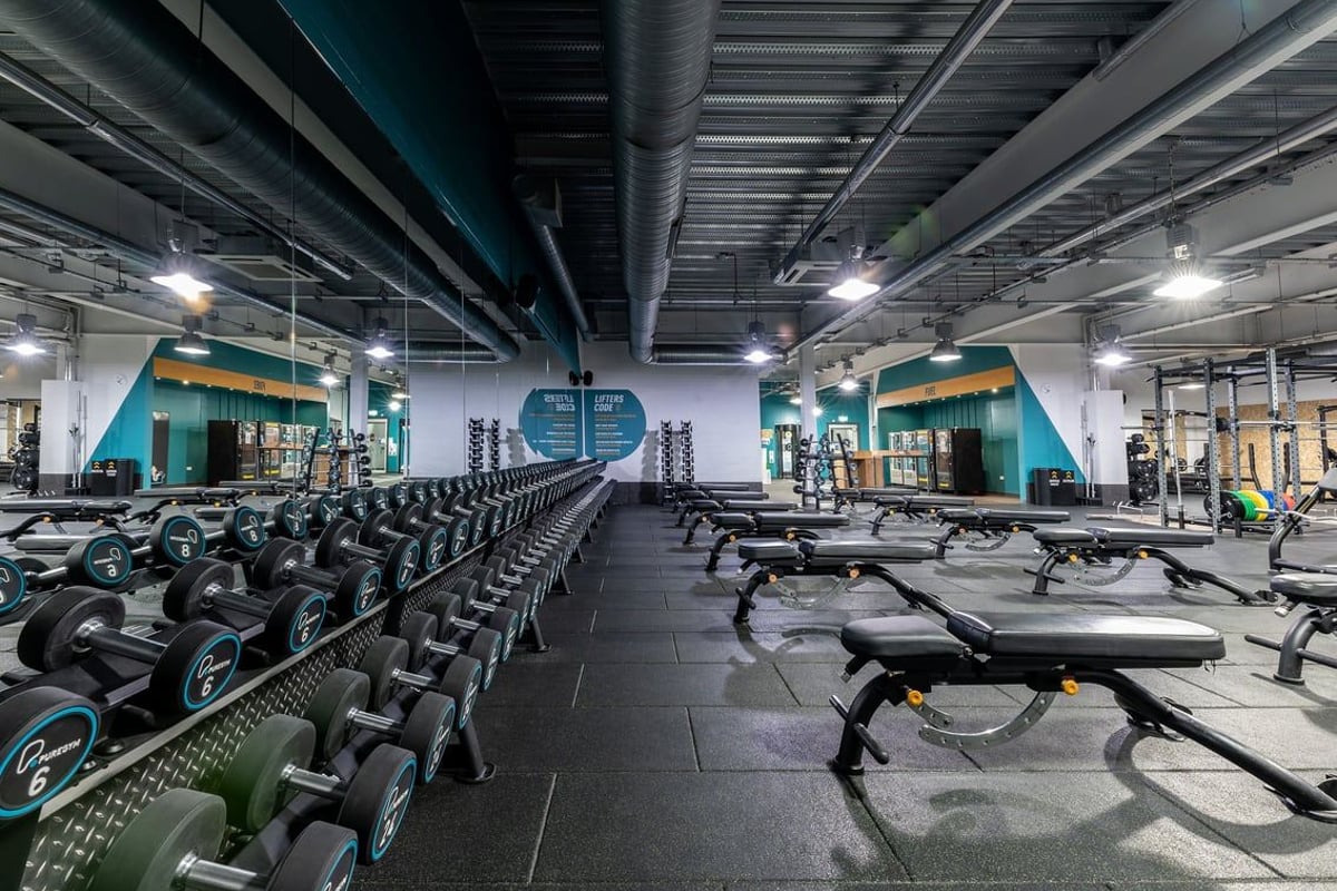PureGym Nottingham Beeston: Rows of stationary bikes, treadmills, weight benches, dumbbell racks in a dimly lit gym interior.