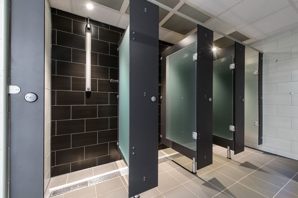 PureGym Bedford Heights: Changing room with private cubicles, tiled flooring, and showers.
