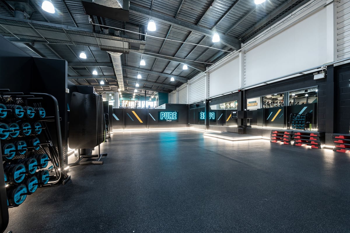 PureGym Milton Keynes Winterhill: Industrial fitness studio with weight racks, medicine balls, and rubberized floor.