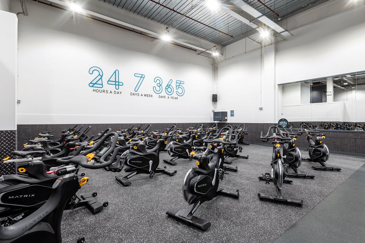 PureGym Newport Wales: Rows of stationary bikes, exercise cycles, and rubberized flooring in a gym studio space.