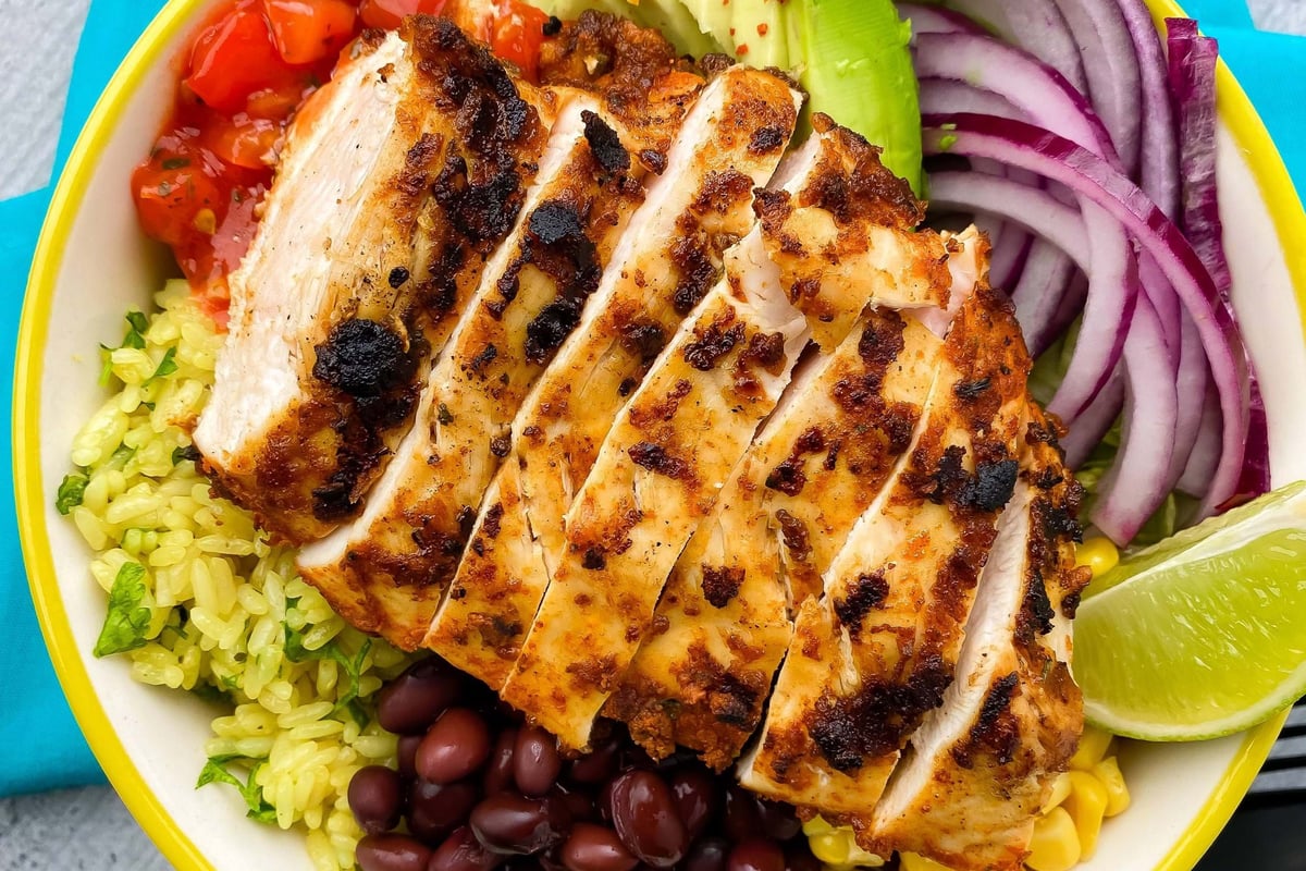 Grilled chicken breast slices with avocado, black beans, corn, rice, red onion, salsa, and