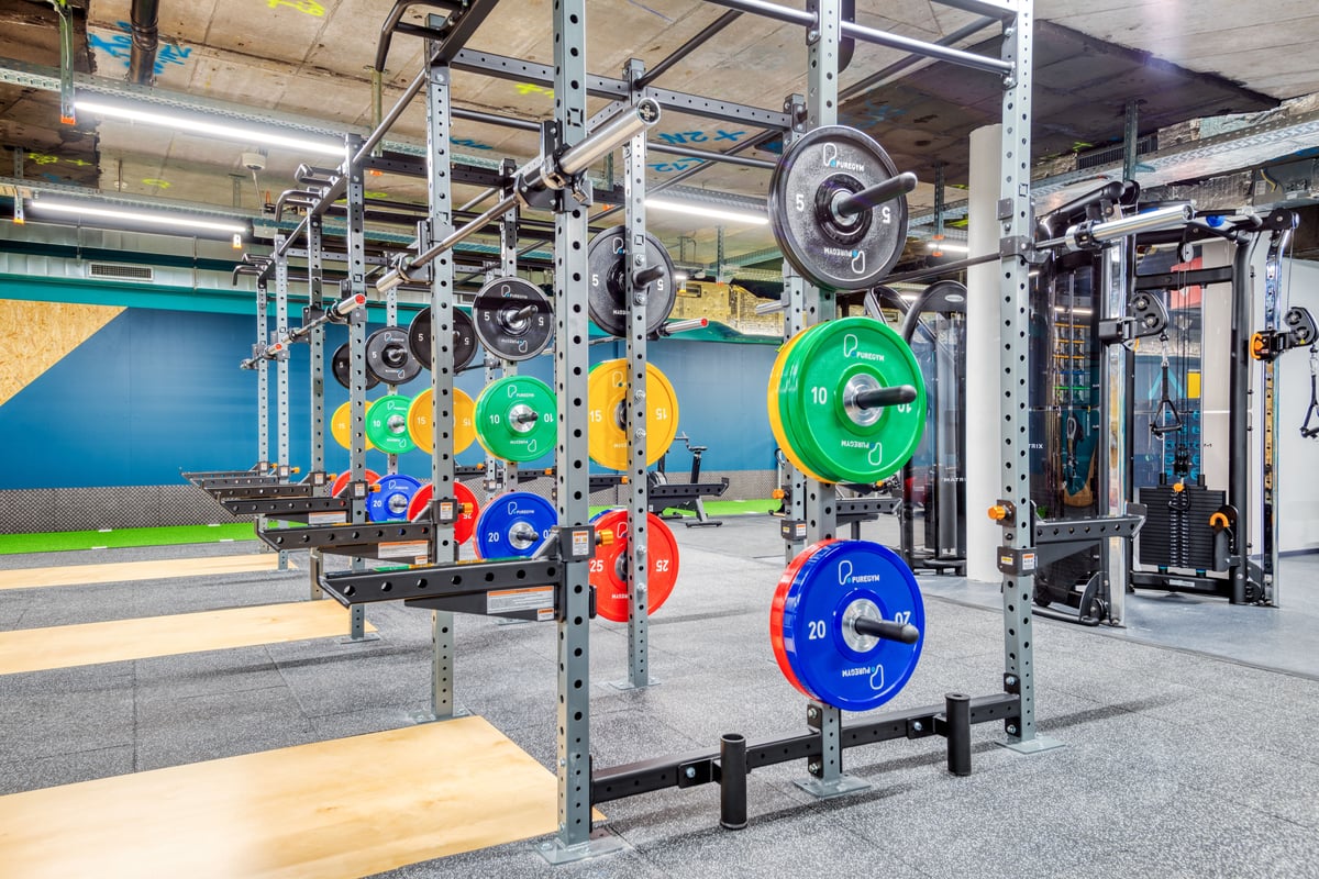 Une rangée de supports en acier chargés de disques bumper colorés dans une gym