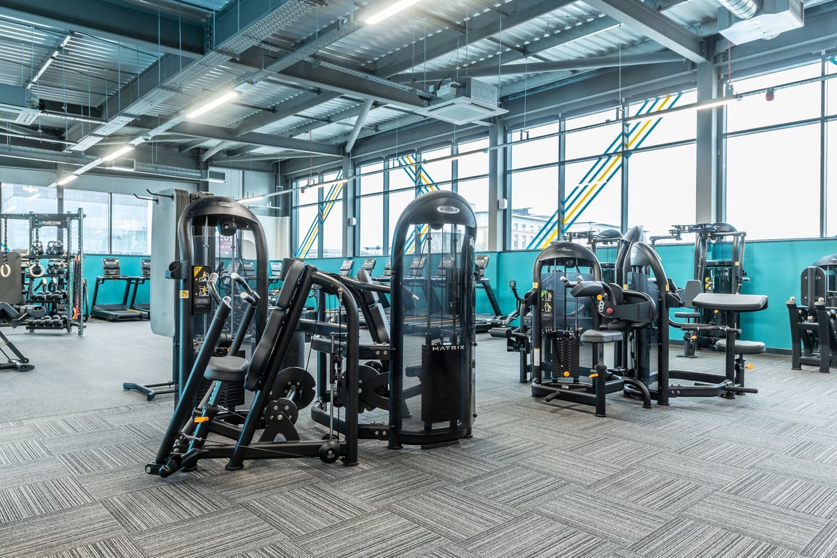 PureGym Plymouth Derriford: Resistance training equipment, cable machines, benches, and rubberized flooring in a gym setting.