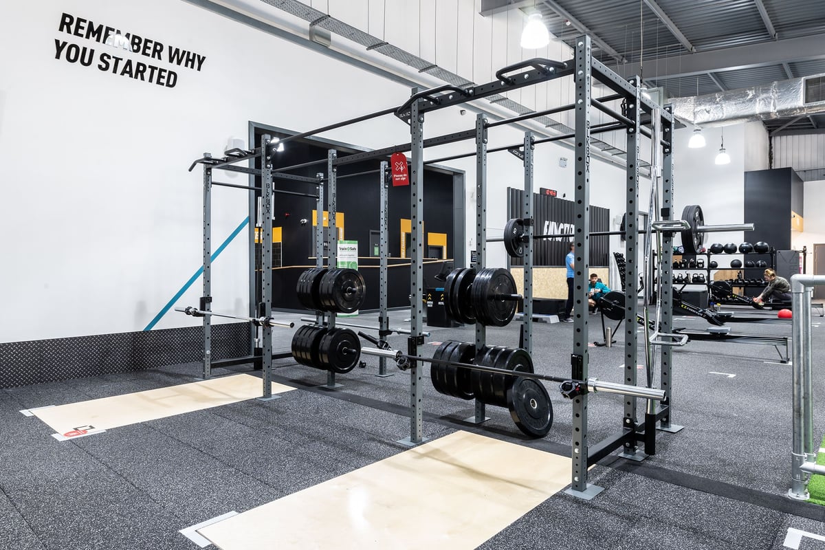 PureGym Warrington Central: Squat racks, weight plates, and storage racks for free weights in a gym setting.