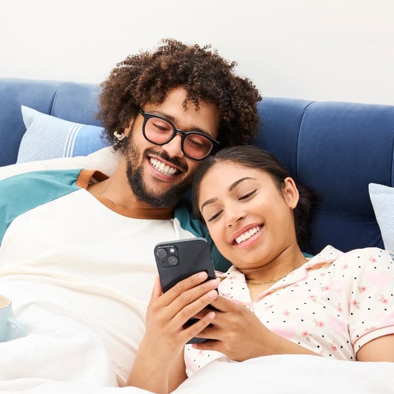 Ein Paar entspannt im Bett und schaut auf ein Smartphone
