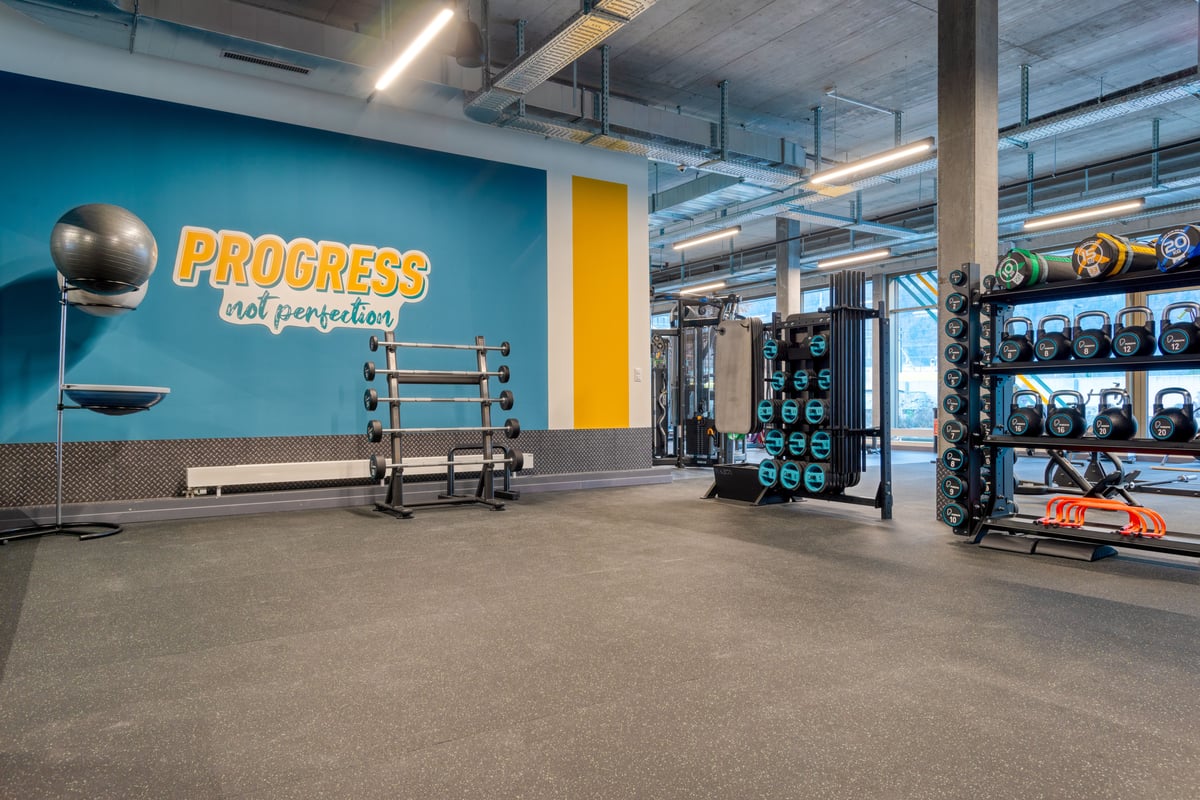 PureGym Altdorf: kettlebells, barbells and swiss ball in a gym with rubberised floor in the foreground and motivational slogan on the wall