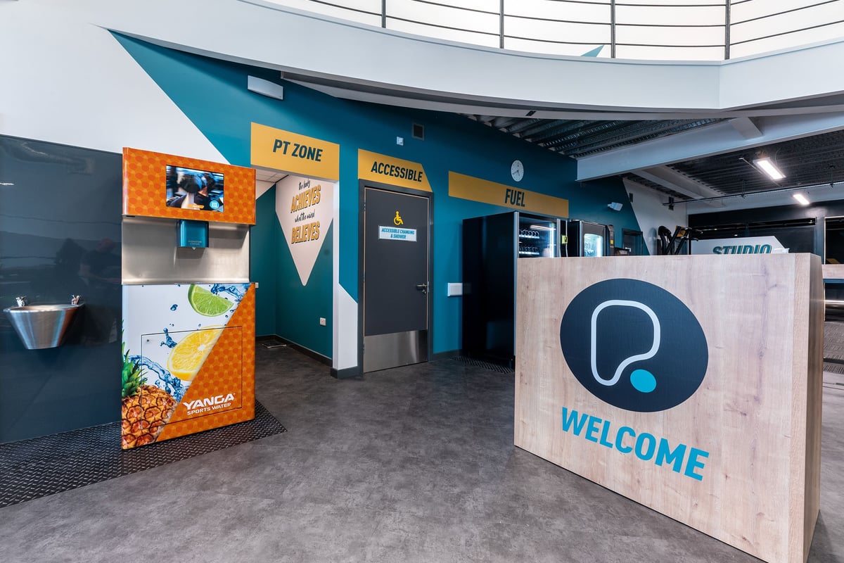 PureGym Coleraine: Welcome podium, water fountain, vending machines, and the entrance to the personal training zone.