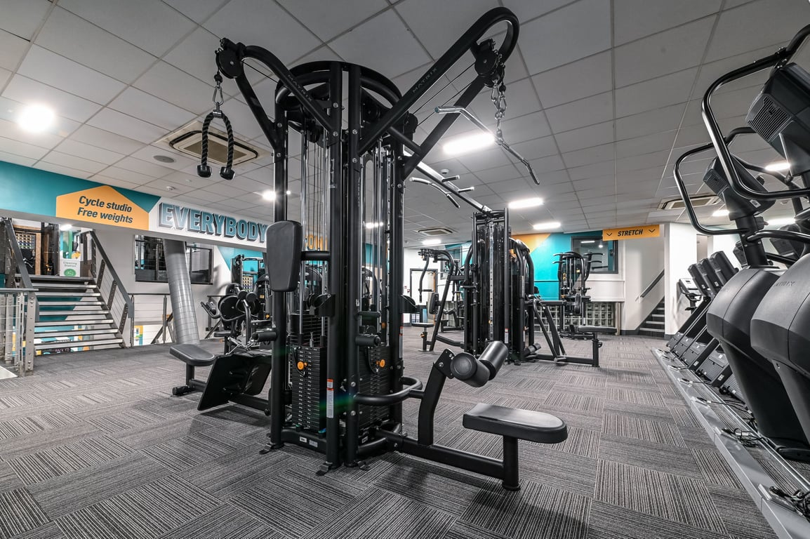 PureGym London Piccadilly: Weight machines, cable machines, benches, and rubberized flooring in a gym with teal accent walls.