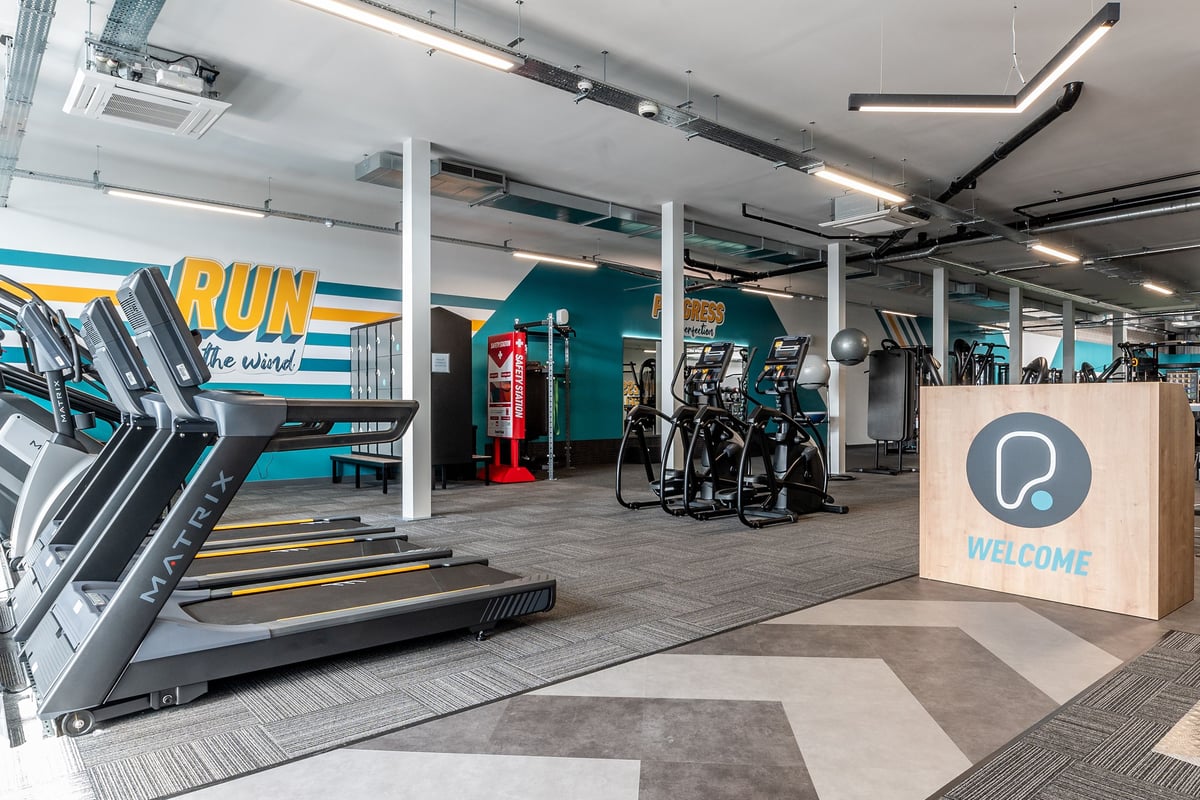 PureGym Sittingbourne: Treadmills, exercise bikes, weight racks, teal branding, and wooden welcome sign.