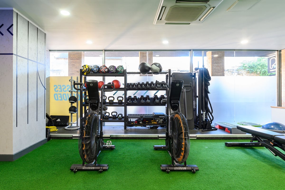 PureGym Oxford Central: Racks of free weights, resistance machines, turf flooring in a fitness studio.