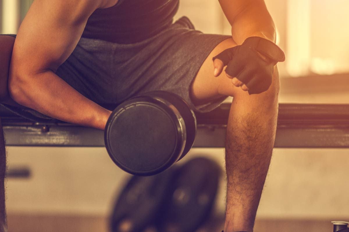 Mann sitzt auf Bank und hält Hantel während Indoor-Krafttraining.