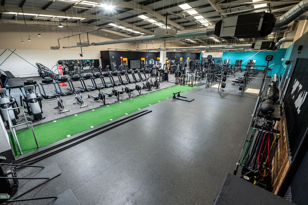 PureGym Weston-super-mare: Rows of treadmills, exercise bikes, green turf area, free weights, resistance machines.