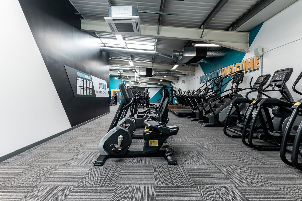 PureGym Gloucester Retail Park: Rows of cardio machines, weight benches, and strength equipment in a modern gym studio.
