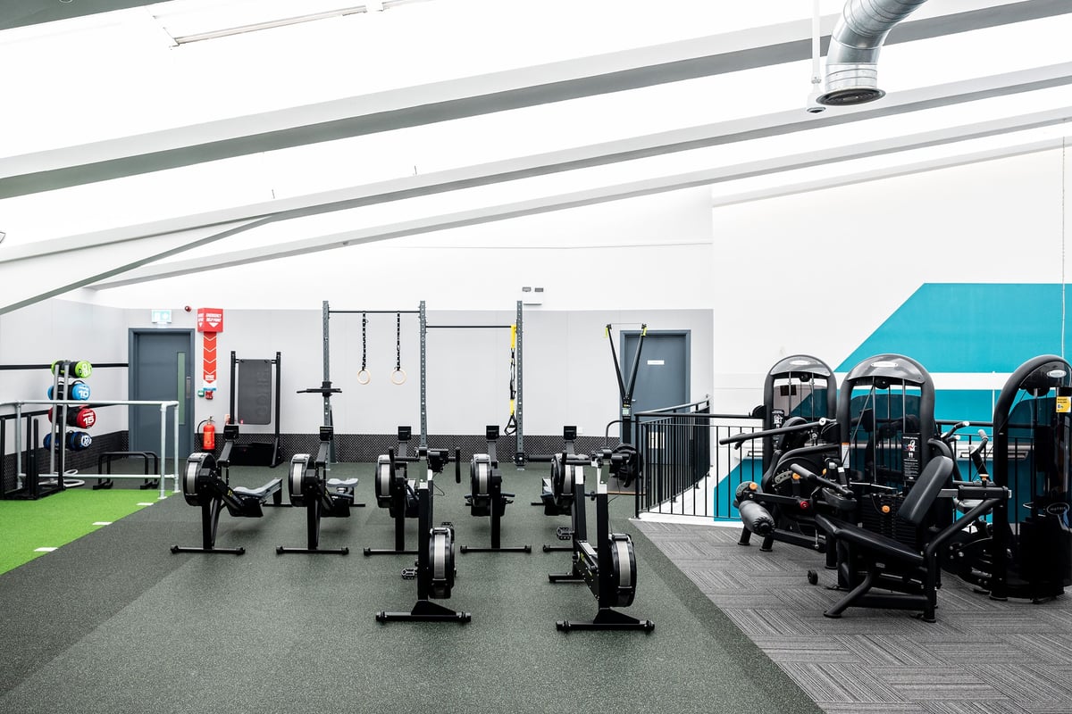 PureGym Belfast Boucher Road: Gym with rows of weight racks, benches, resistance machines, and rubberized flooring.