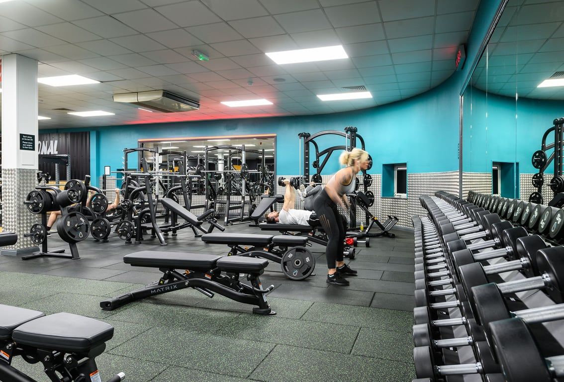 PureGym Waterlooville: Strength training area with weight machines, free weights, benches, and mirrors.
