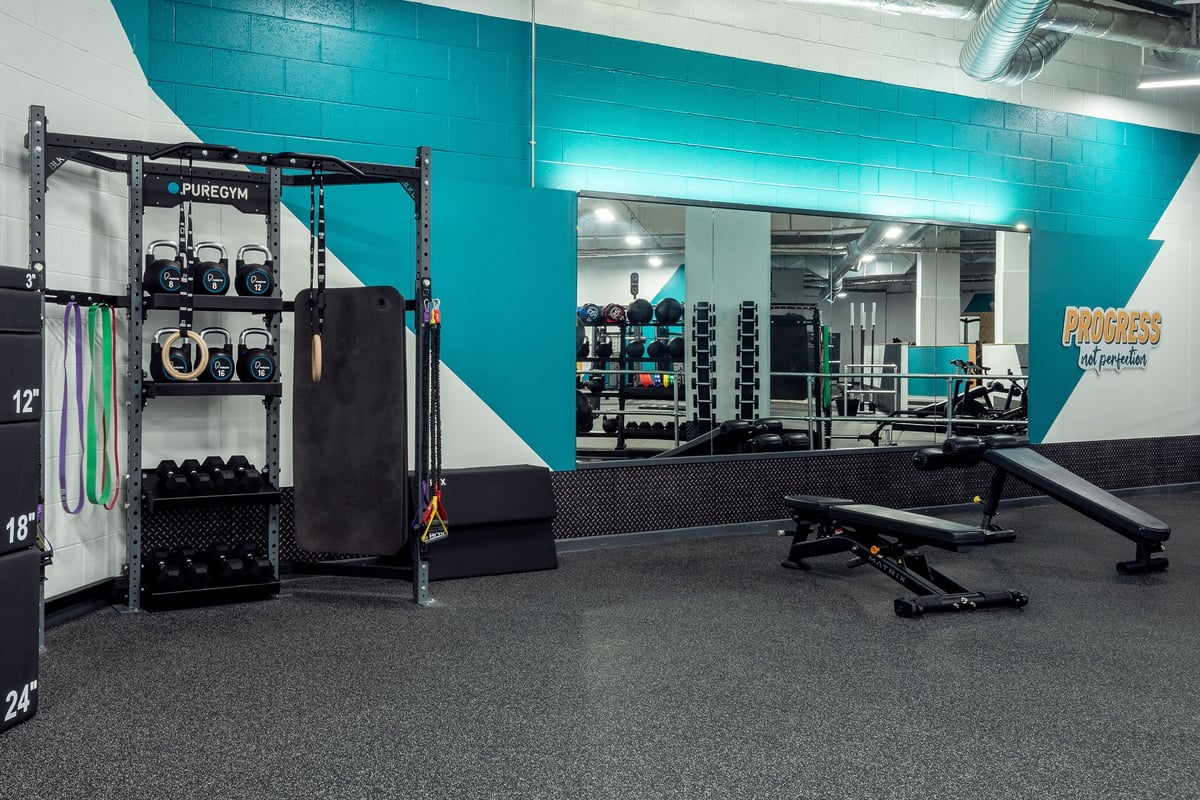 PureGym Leicester St Georges Way: Free weights, machines, benches, and teal colour scheme in a modern gym studio interior.