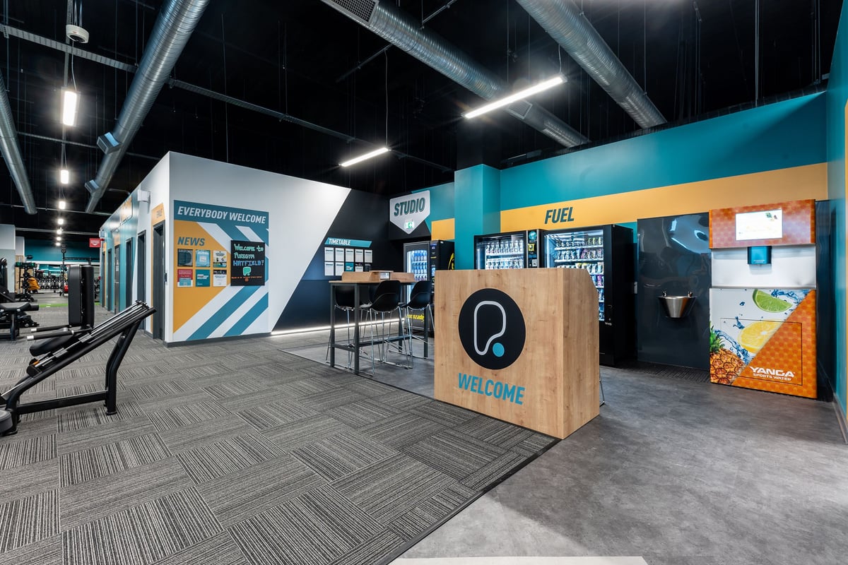 PureGym Hatfield: Trade show exhibition area with welcome desk, information kiosks, and branded graphics.