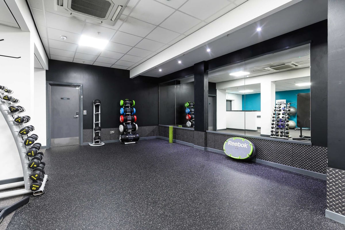 PureGym Glasgow Shawlands: Free weights and core board on a rubberised floor in a gym studio.