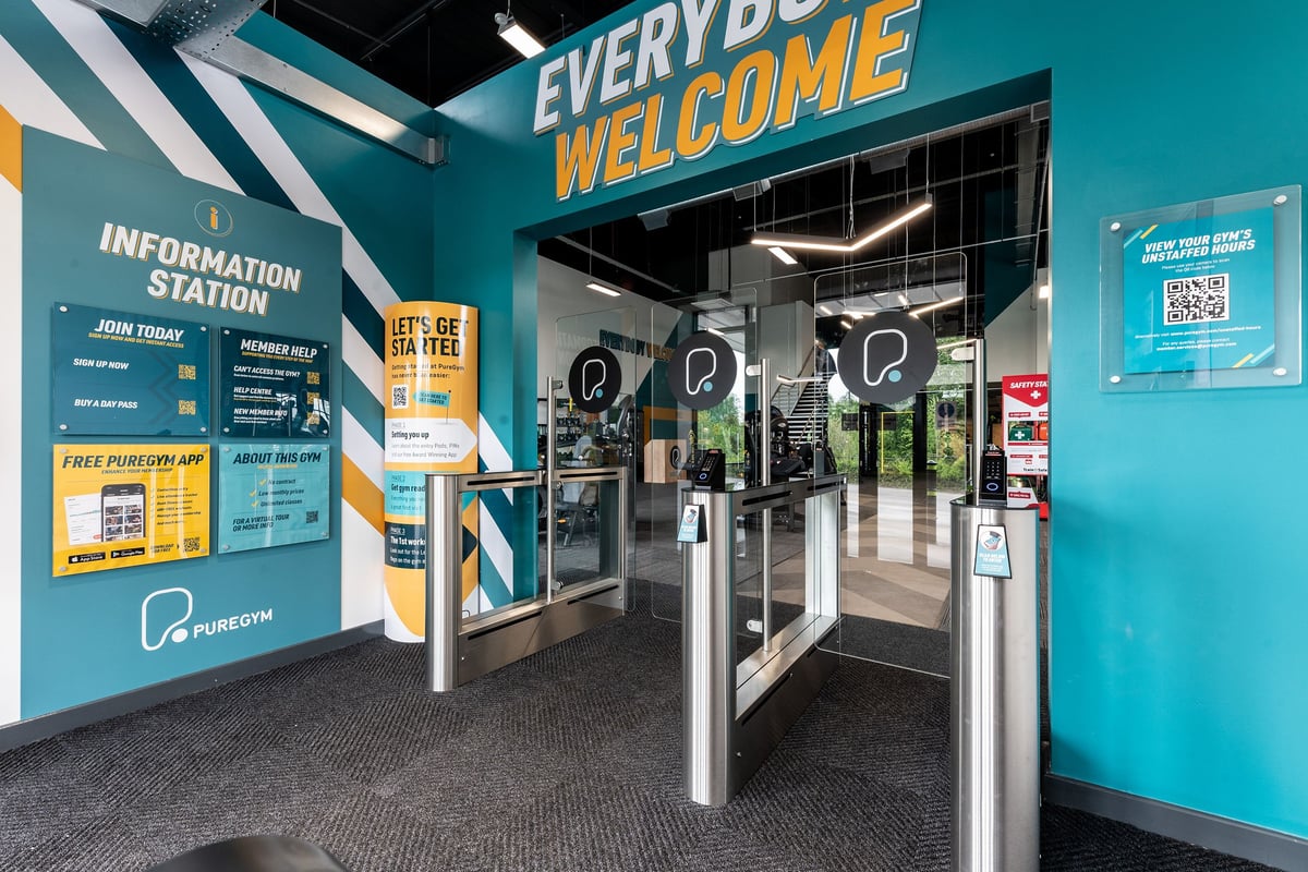 PureGym Doncaster: Turnstiles, information station, and self-service kiosks in a bright gym entryway.