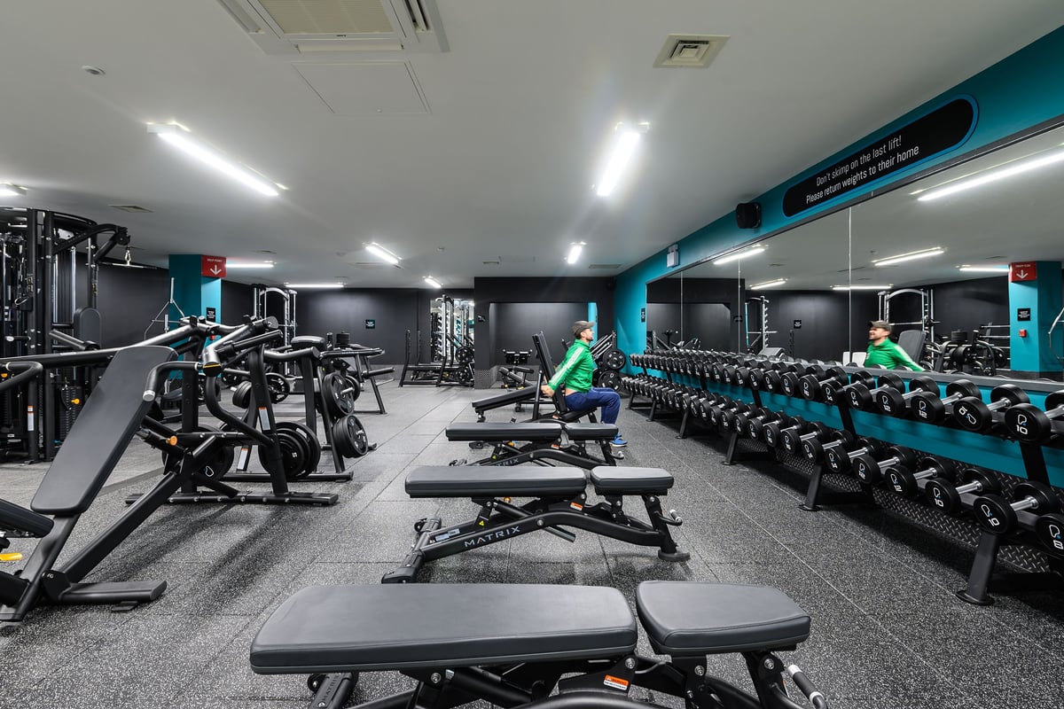PureGym Didcot: Rows of weight benches, squat racks, free weights, and resistance machines in a dimly lit studio.